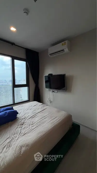 Modern bedroom with city view, featuring a wall-mounted TV and air conditioning.