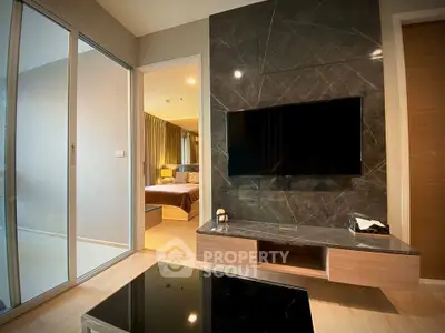 Modern living room with sleek TV wall and view into cozy bedroom