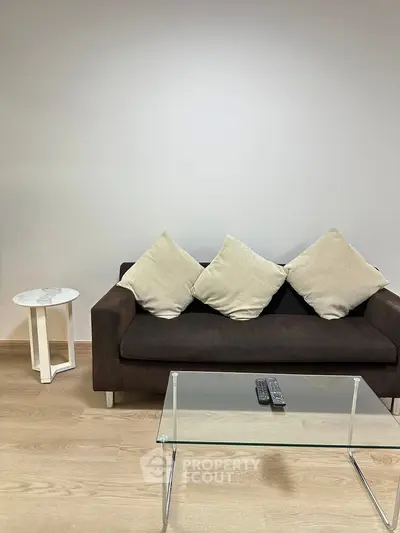 Modern living room with sleek sofa, glass coffee table, and minimalist decor.