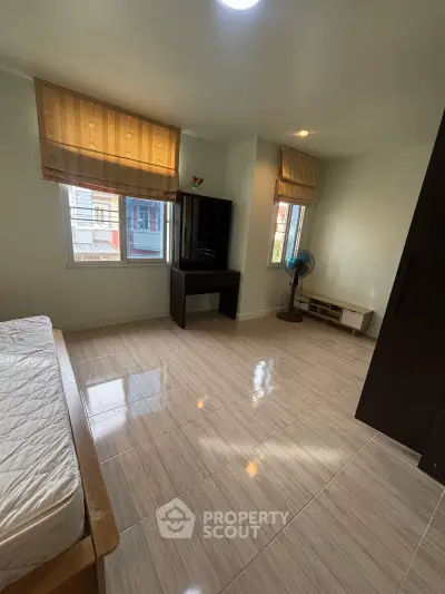 Spacious bedroom with large windows and modern furnishings in a bright apartment.