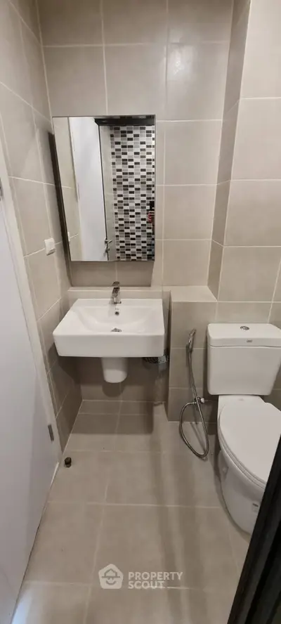 Modern bathroom with sleek sink and toilet in tiled interior.