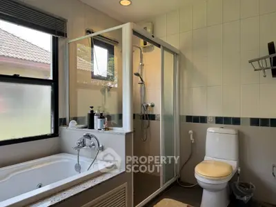 Modern bathroom with bathtub and shower in a bright, tiled space.