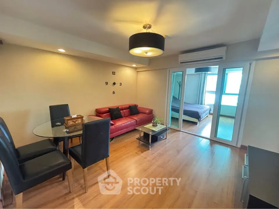 Spacious living room with modern decor and open layout, featuring a red sofa and dining area.
