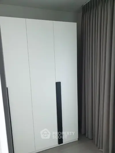 Modern minimalist wardrobe in a stylish bedroom with floor-to-ceiling curtains.