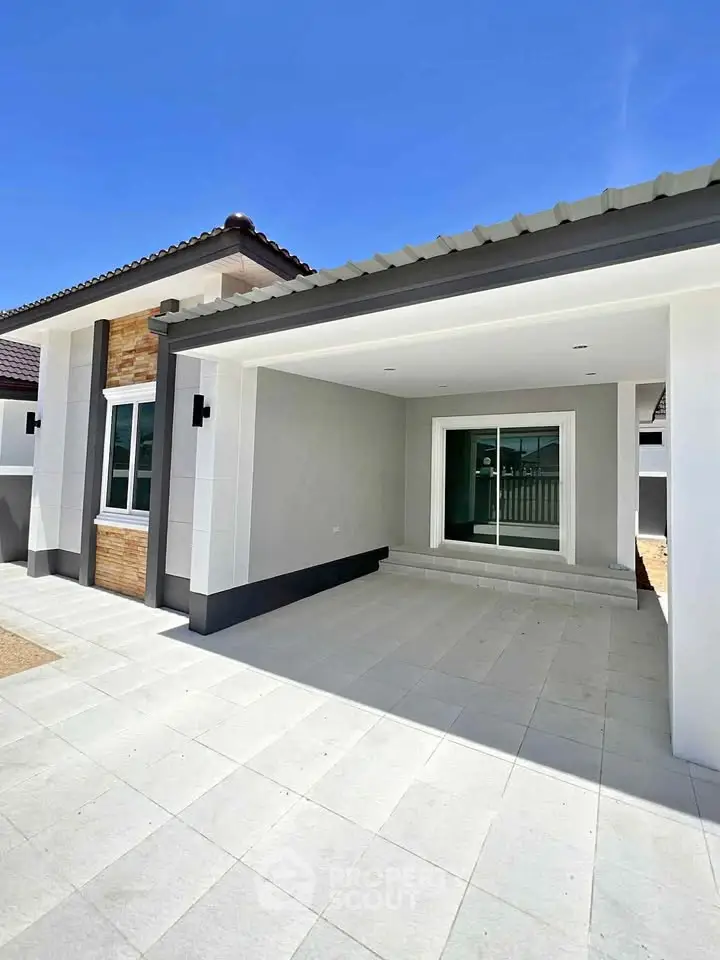 Modern single-story house with spacious driveway and sleek design.