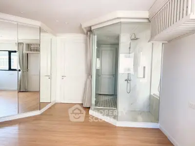 Spacious modern bedroom with glass shower and mirrored closet doors