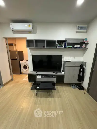 Modern living room with TV, air conditioning, and stylish shelving in a cozy apartment.