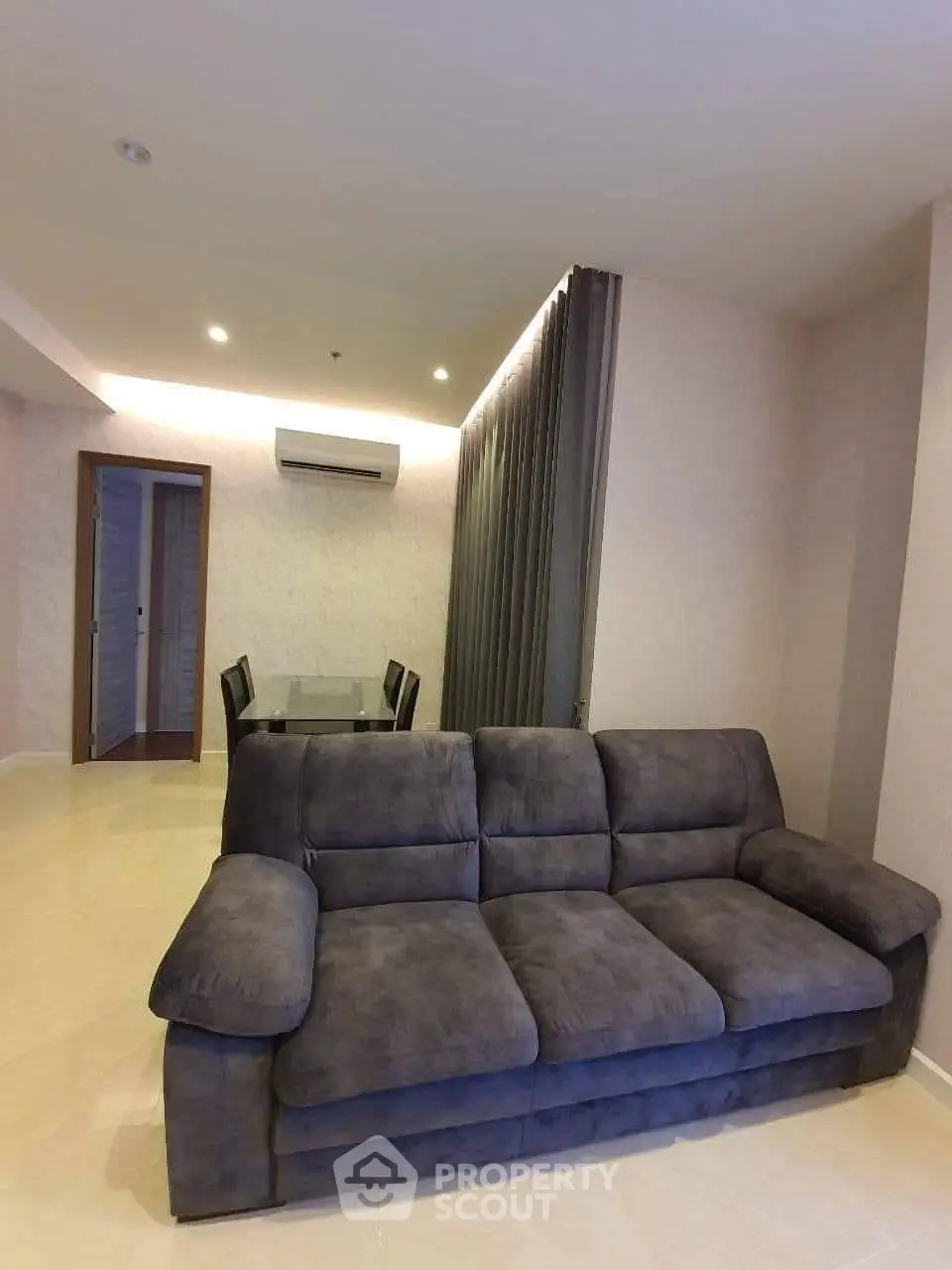 Modern living room with plush gray sofa and dining area in open layout apartment.