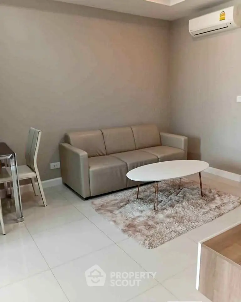 Modern living room with beige sofa, sleek coffee table, and air conditioning unit.