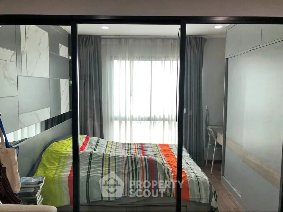 Modern bedroom with glass partition and colorful bedding in a stylish apartment.