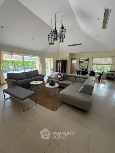 Spacious living room with modern furniture and large windows overlooking a lush garden.
