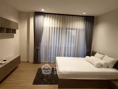 Spacious modern bedroom with elegant decor and large window for natural light.