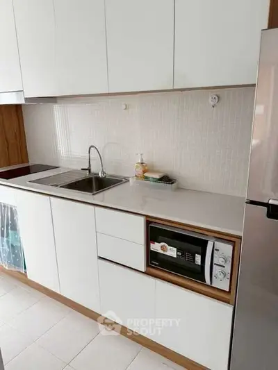 Modern kitchen with sleek white cabinets and built-in microwave