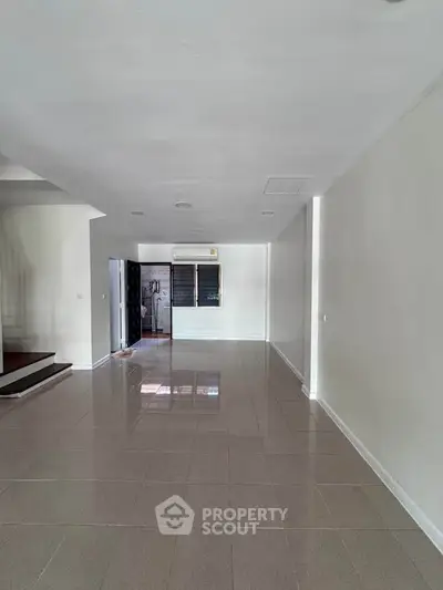 Spacious empty living room with tiled floor and air conditioning, ready for customization.