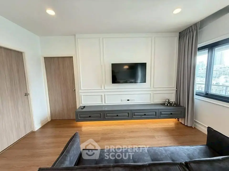 Modern living room with wall-mounted TV and sleek furniture in a stylish apartment.