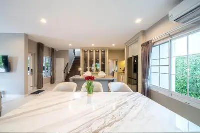 Luxurious open-plan living room with elegant marble dining table and modern kitchen.