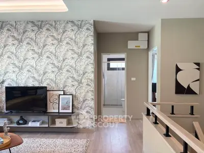 Stylish living room with modern decor and open layout, featuring a TV and elegant wallpaper.