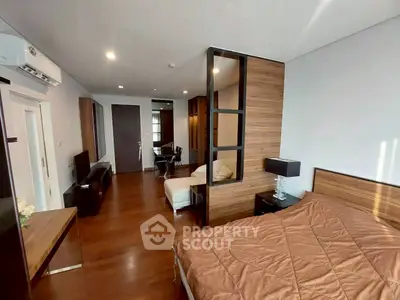 Spacious modern bedroom with wooden flooring and stylish decor in a luxury apartment.