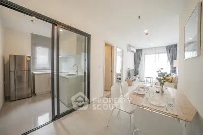 Modern open-plan living and dining area with glass partition kitchen in a bright apartment.