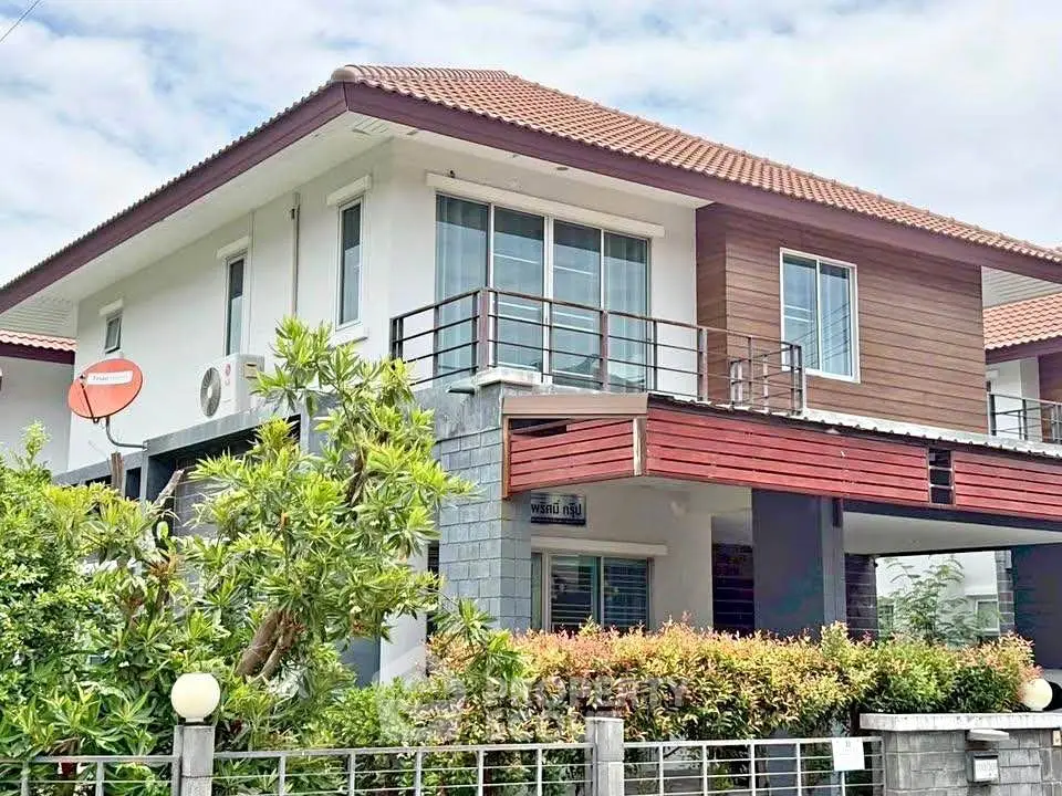 Modern two-story house with balcony and lush greenery