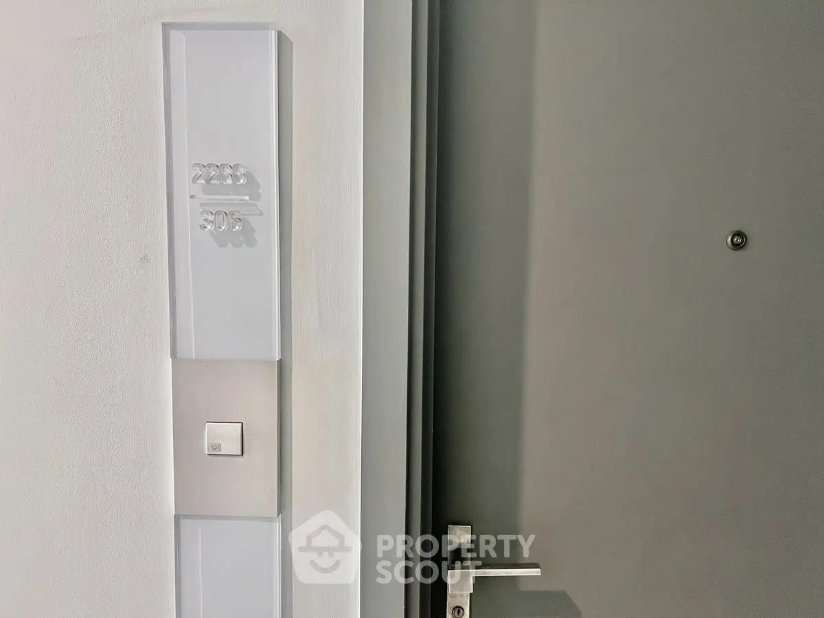 Modern apartment entrance with sleek door and stylish doorbell panel.