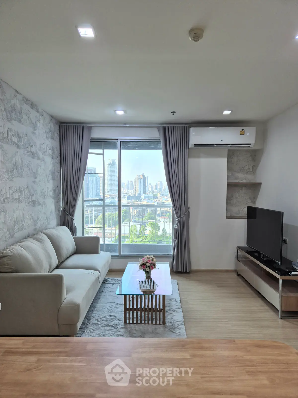 Modern living room with city view, featuring a cozy sofa, TV, and large window for natural light.