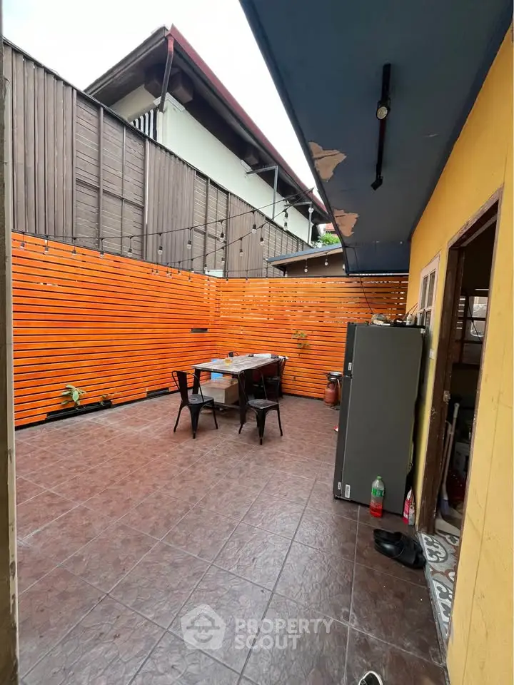 Charming outdoor patio with vibrant orange privacy fence and cozy seating area.