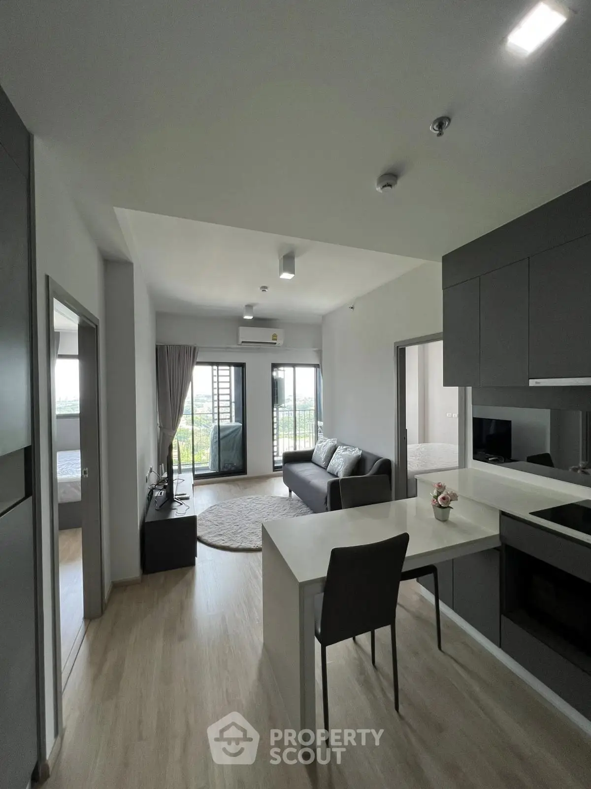 Modern open-plan living room with sleek kitchen and balcony view in stylish apartment.
