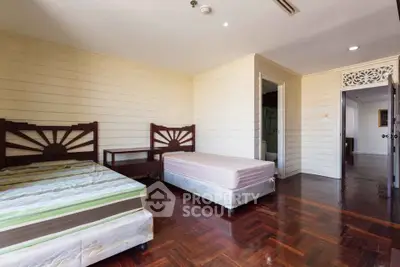 Spacious bedroom with wooden flooring and twin beds in a cozy real estate property.