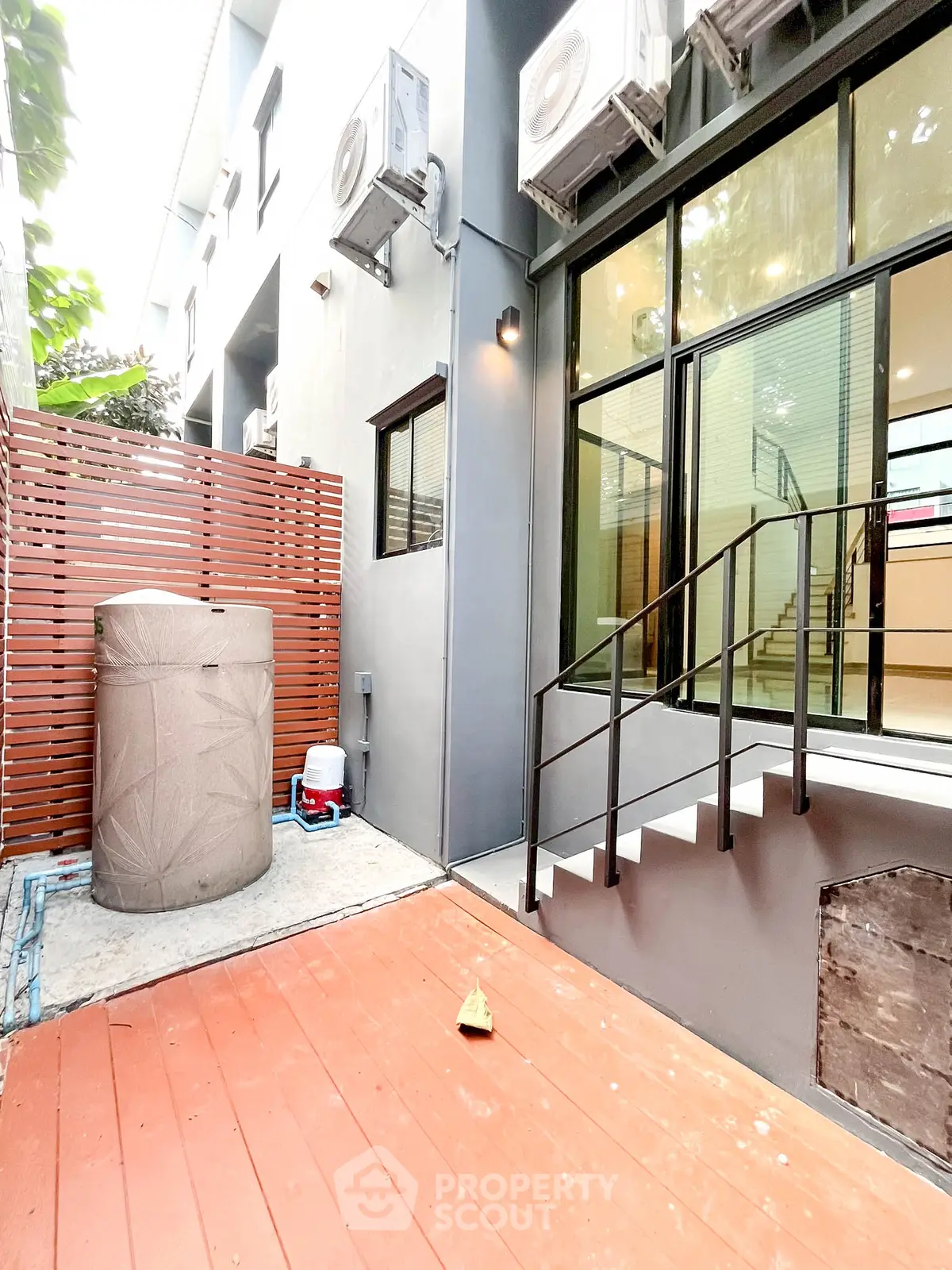Modern townhouse exterior with wooden deck and air conditioning units