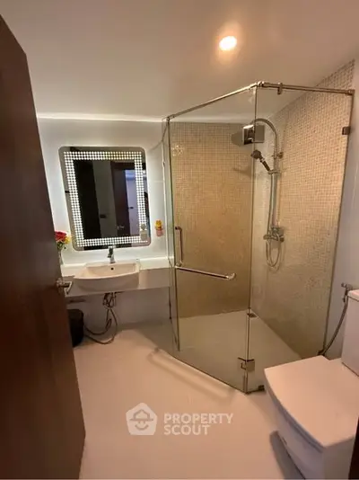 Modern bathroom with glass shower and illuminated mirror