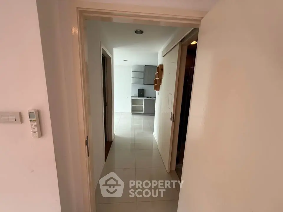 Modern apartment entrance with sleek kitchen view and tiled flooring.