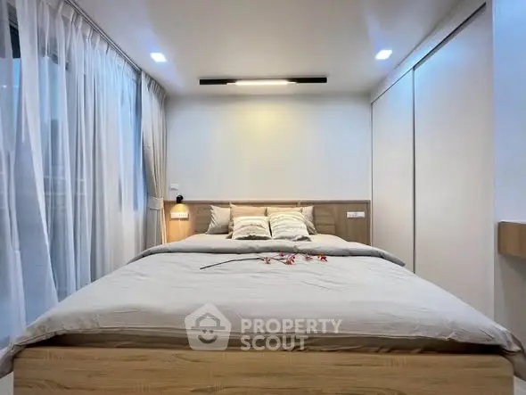 Modern bedroom with cozy lighting and elegant decor, featuring a comfortable bed and stylish curtains.