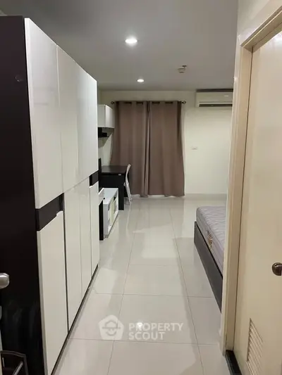 Modern studio apartment with sleek furniture and neutral decor, featuring a comfortable bed and workspace.