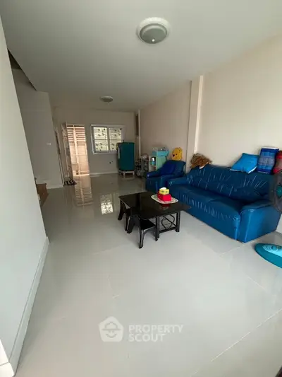 Spacious living room with modern blue sofa and sleek tiled flooring