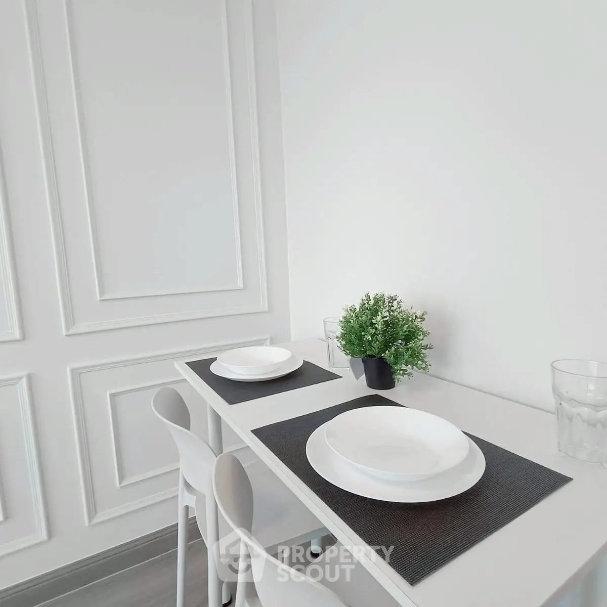 Elegant minimalist dining area with white decor and modern table setting.