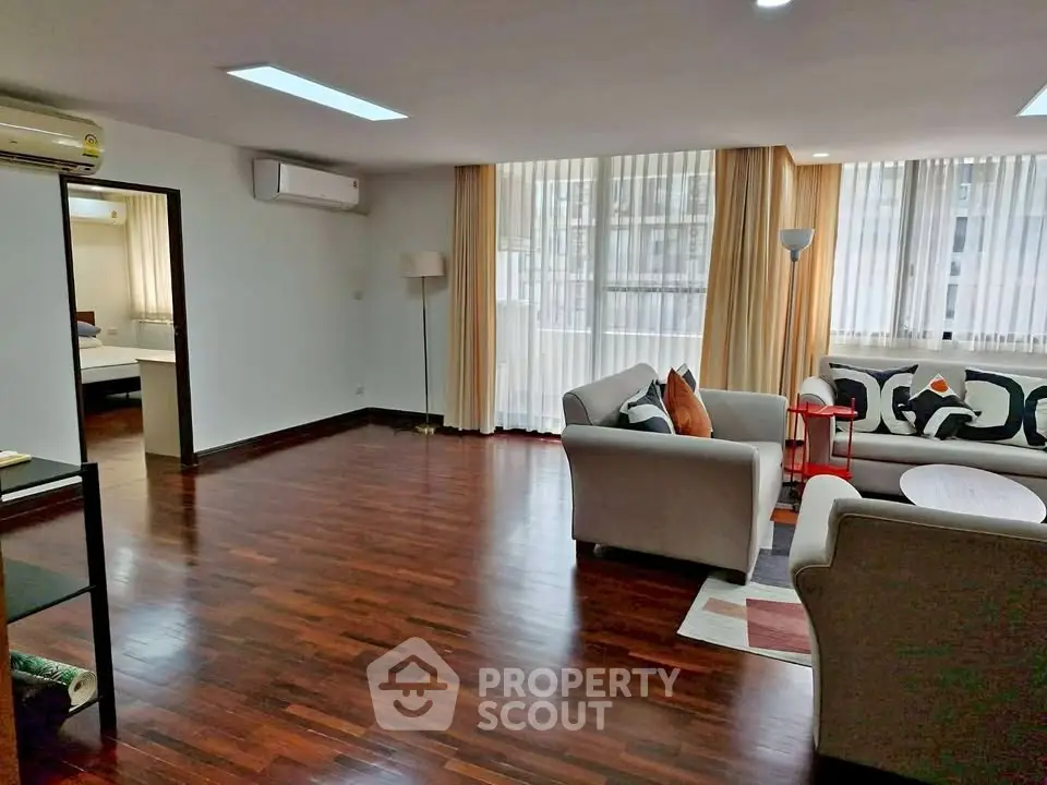 Spacious living room with elegant hardwood floors and modern furniture in a bright apartment.