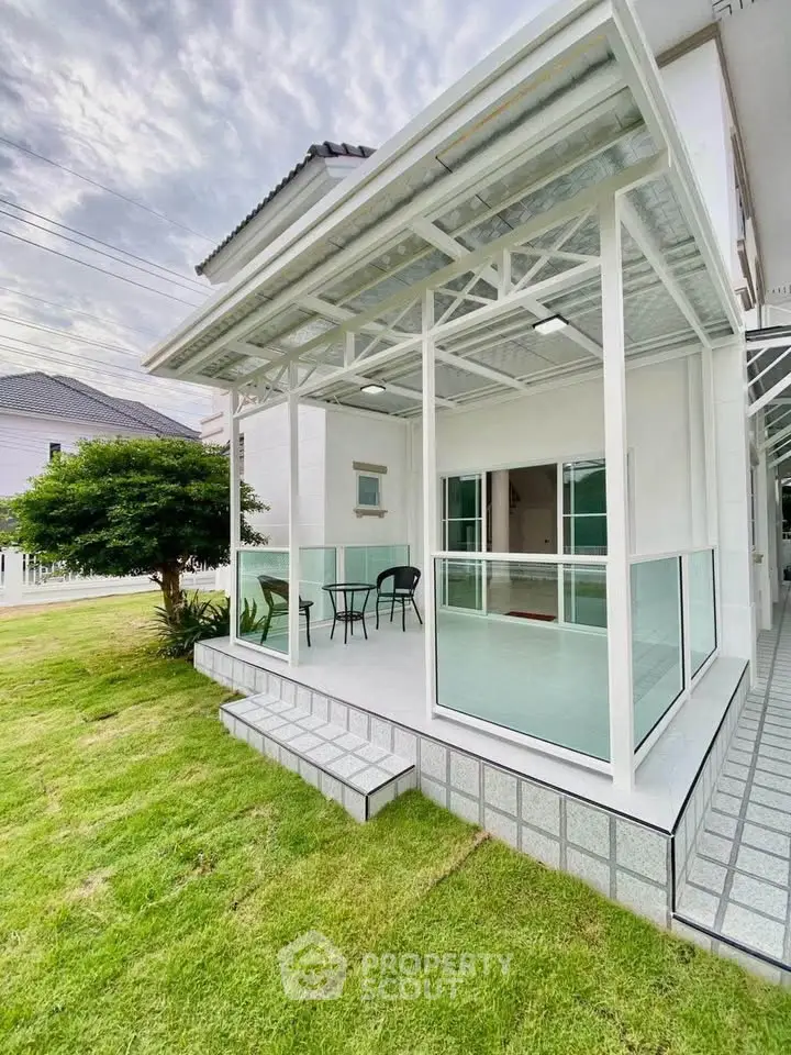 Modern home exterior with glass patio and lush green lawn, perfect for outdoor relaxation.