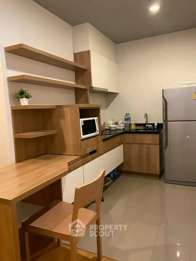 Modern kitchen with sleek cabinetry and stainless steel fridge in a cozy apartment setting.