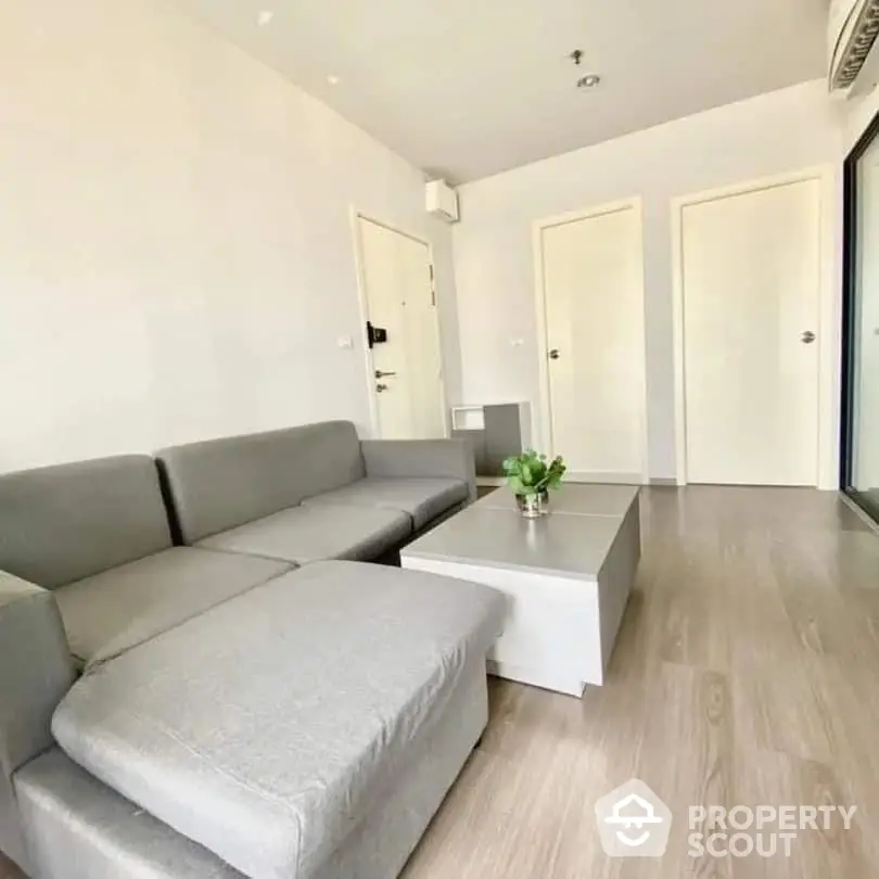 Spacious and modern living room with large grey sectional sofa, sleek white coffee table, and elegant wooden flooring, perfect for urban living.