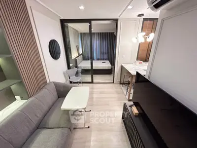 Modern living room with sleek furniture and open layout leading to a cozy bedroom.