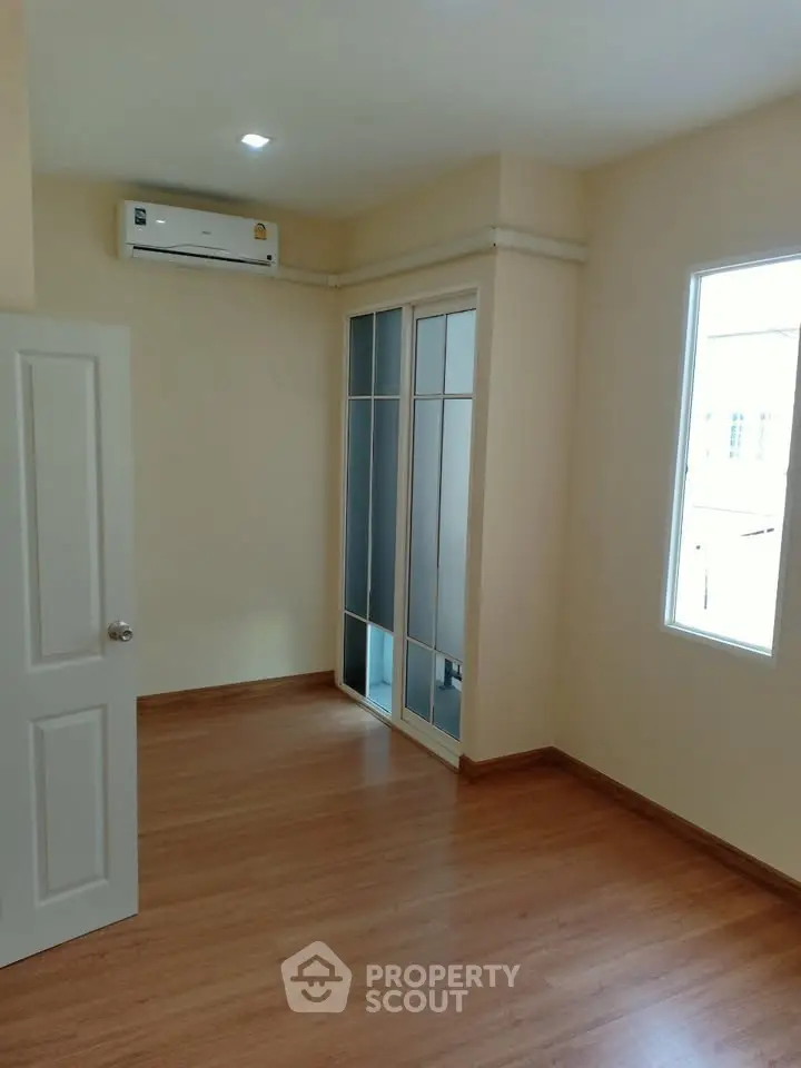 Bright and airy bedroom with wooden flooring and built-in wardrobe.