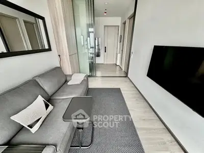 Modern living room with sleek grey sofa and wall-mounted TV in contemporary apartment.