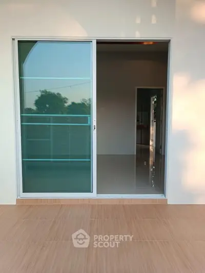 Spacious balcony with sliding glass doors and serene outdoor view