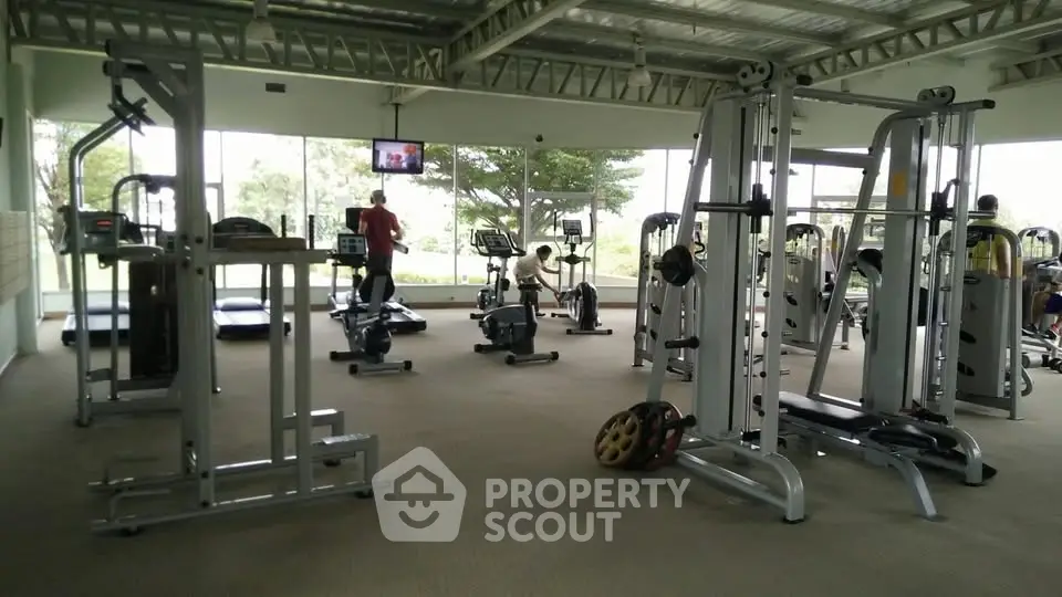 Spacious gym with modern equipment and large windows offering scenic views.