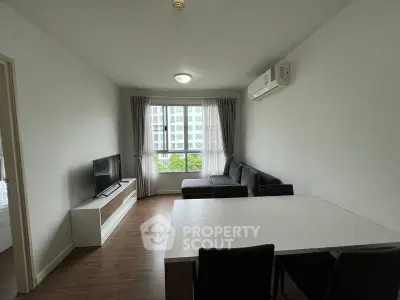 Modern living room with sleek furniture and large window offering city views, perfect for urban living.