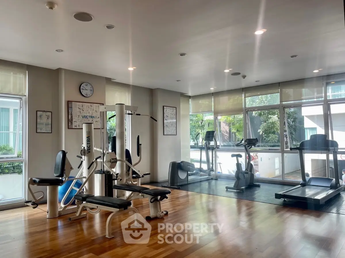 Modern gym with fitness equipment and large windows in a residential building.