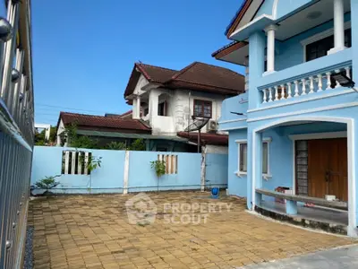 Charming blue two-story house with spacious paved driveway and traditional architecture.