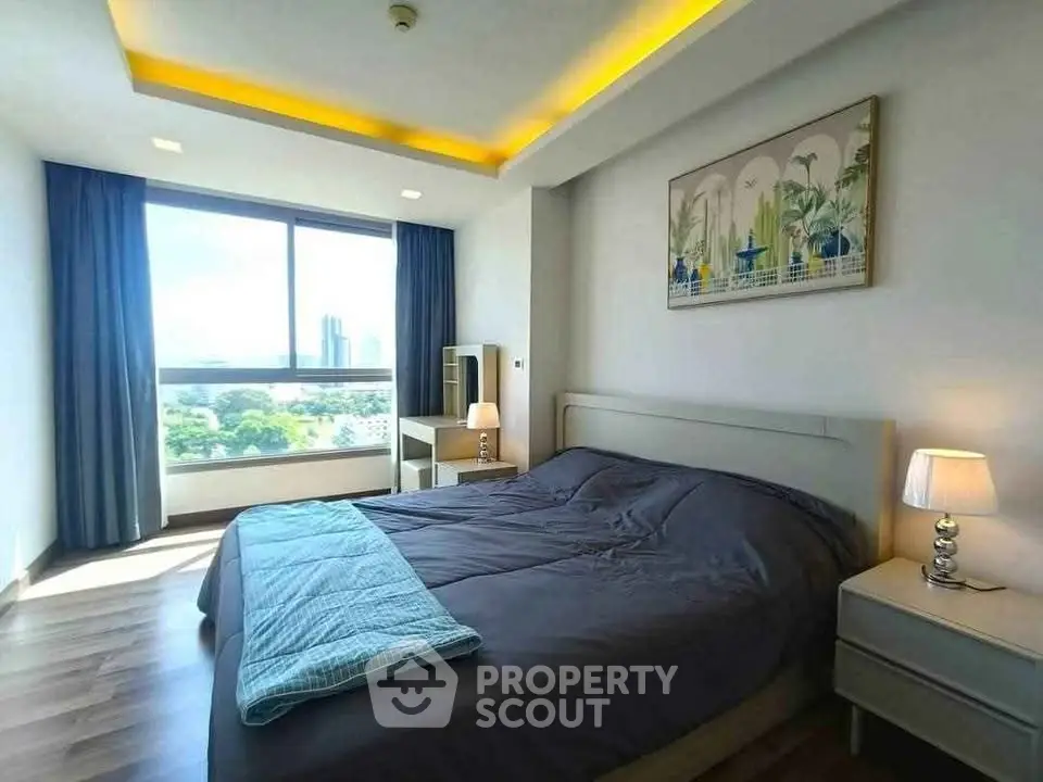 Bright and spacious bedroom with large window and modern decor in high-rise apartment.