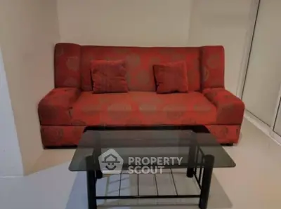Cozy living room with red sofa and glass coffee table in modern apartment.